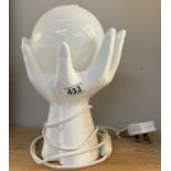 A white glazed pottery pair of hands holding spherical glass shade table lamp. In working order
