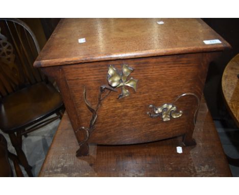 An Arts and Crafts oak lidded box, possibly coal or kindling, unlined, having foliate applique decoration and brass ring hand
