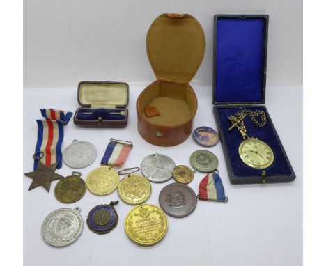 A collection of medals and badges, a stick pin and a fob watch 