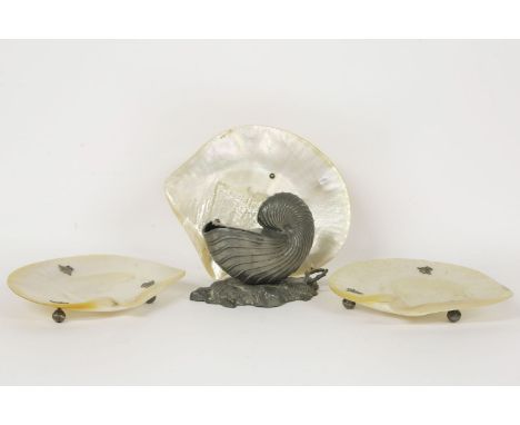 Three large mother of pearl shells, with metal ball feet, 22cm wide, and a pewter Nautilus shell spoon warmer (4)