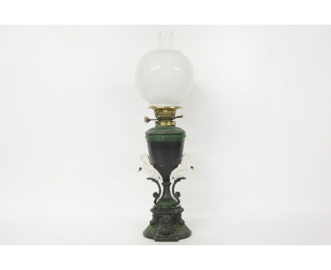 A classical revival metal bodied oil lamp, cast with swans and masks, with a Hinks & Sons patent, burner, flu, and shade