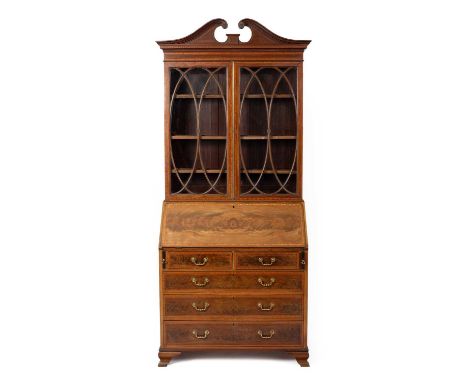 An Edwardian mahogany and satinwood inlaid bureau bookcase, the broken swan neck pediment above glazed panel doors on a burea