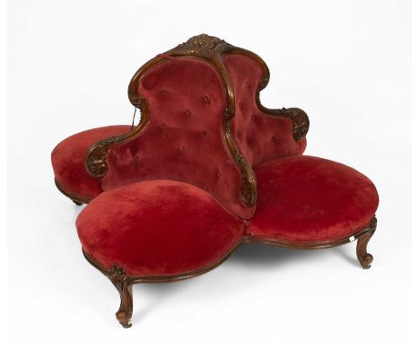 A Victorian carved mahogany framed conversation seat, the four seats with button backs set on scroll carved legs with white c