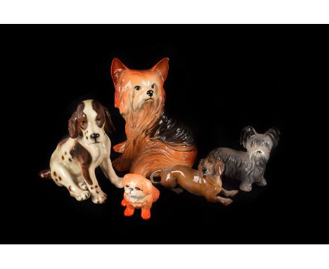A collection of ceramic and pottery dogs, including a Beswick begging Pekinese, a Coppercraft Yorkshire terrier and another s