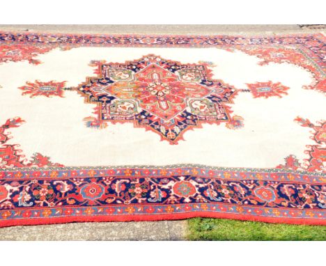 A very large Indian woollen carpet, with red and white ground and bright colour medallion to centre and corners, bearing labe