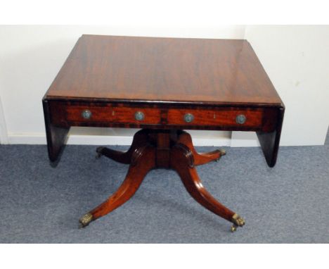 An Edwardian period mahogany sofa table, having drop leaf sides, two drawers to frieze and dummy drawers to reverse, on casto