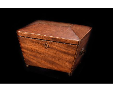 A mid 19th century mahogany tea caddy, sarcophagus shaped on four brass bun feet, some repairs
