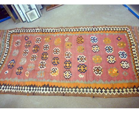 A vintage Persian Kilim carpet, the long red rug with red ground and geometric medallions, some damages, approx 300cm long
