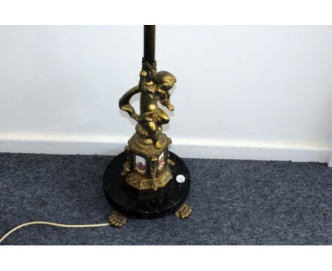 An Edwardian period brass standard lamp base, the column stem on base with cherub and four enamelled panels, on circular marb