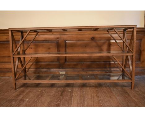 An X framed teak console table with three plate glass tiers. H.72 W.140 D.33cm 