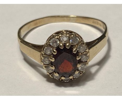 A 9 CARAT GOLD RING WITH CENTRE GARNET SURROUNDED BY CUBIC ZIRCONIAS SIZE R/S 