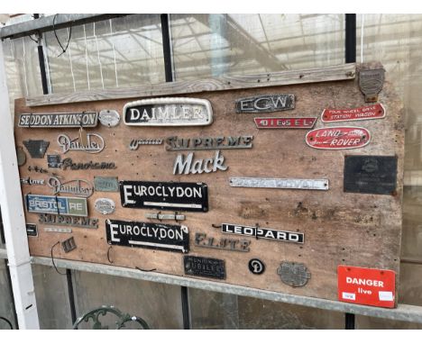 A LARGE WOODEN BOARD CONTAING A LARGE ASSORTMENT OF VINTAGE CAR AND VEHICLE BADGES TO INCLUDE DAIMLER, LAND ROVER, SUPREME AN