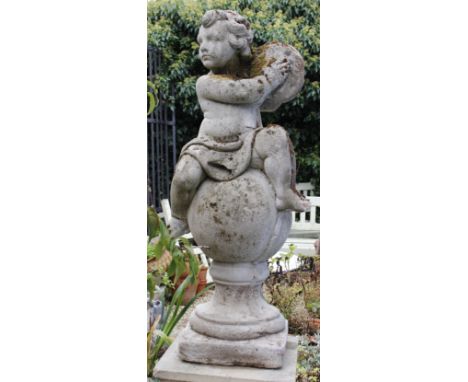 A RECONSTITUTED STONE SCULPTURE OF A PUTTI playing cymbals whilst perched on a ball finial, all standing on a Haddonstone squ