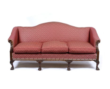 A GEORGE III STYLE MAHOGANY SOFA with camel back, scrolling arms with carved fluted and flower head supports and standing on 