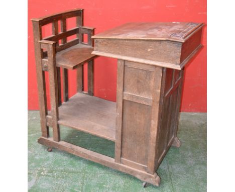 An oak clerk's desk, hinged slope, panelled door cupboard to front, attached seat, ceramic casters.