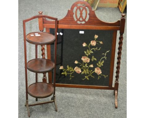 An Edwardian woolwork firescreen (af); an Edwardian mahogany three tier cake stand. (2)