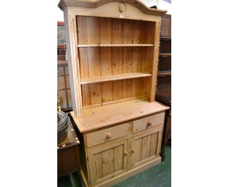 A pine dresser arched pediment, floral carved cartouche, stepped cornice to top, two short drawers over two panel door cupboa