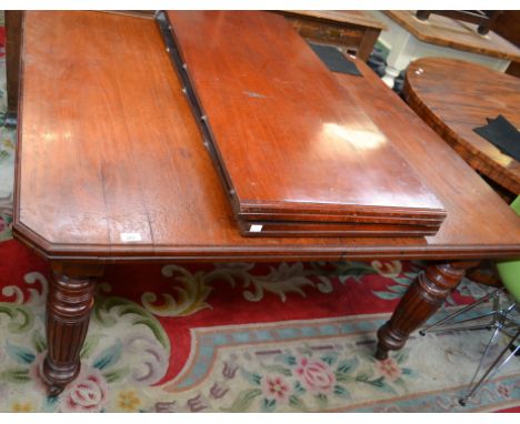 A Victorian Mahogany wind-out dining table, having a rectangular top with canted corners, turned and reeded legs, ceramic cas