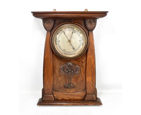 An Arts and Crafts carved oak wall barometer with central silvered dial, flanked by two carved panels and central relief flor