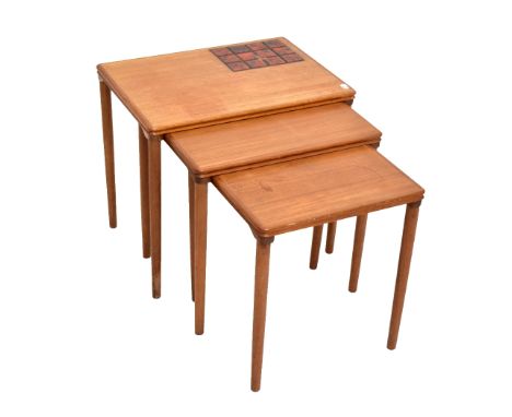 A teak nest of three graduated coffee tables, the largest table with inset tile panel.