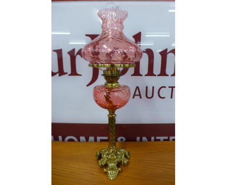 A Victorian brass oil lamp, with cranberry glass reservoir and shade 