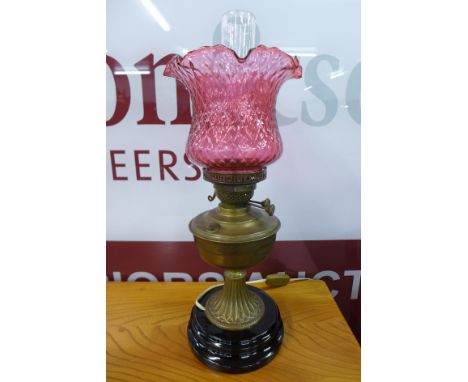 A Victorian brass oil lamp, with a cranberry glass shade 