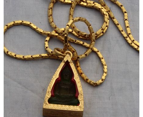 An Indonesian precious yellow metal pendant enclosing carved green stone Buddha, the pendant fashioned as a triangular shrine