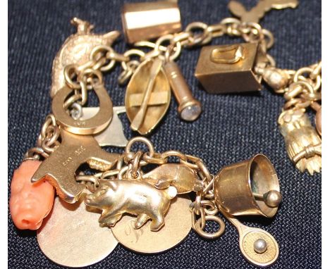 A yellow metal charm bracelet, suspending numerous 9ct. gold charms,&nbsp;the chain formed from alternating round and oval li