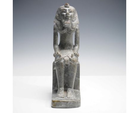A lovely carved stone sculpture depicting a pharaoh seated on a block throne in the classic ancient Egyptian style. The figur