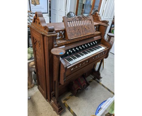 A 19th century Harmonium made by Thomas Organ & Piano Co, Woodstock Canada in an oak carved case with pierced fretwork, candl