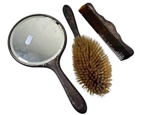 A three piece silver brush and comb set with a mirror 