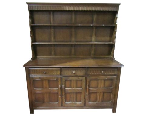 An Ercol dresser enclosed by three panelled doors and three graduated drawers and plate rack over 185H x 150W x 46D 