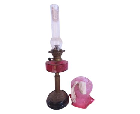 A Victorian brass column oil lamp with a red font and shade, 64cm high