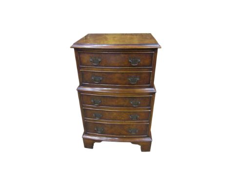 A diminutive reproduction two tier bow front chest of five drawers raised on bracket supports, 70 cm high, 44 x 31cm