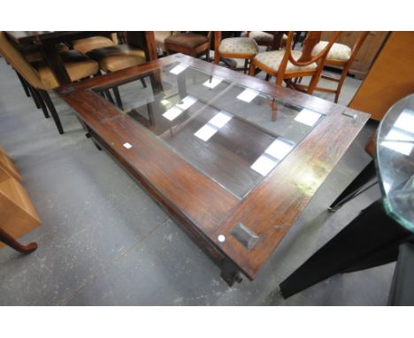 A Large rustic hardwood and glass top coffee table with a wooden under shelf.