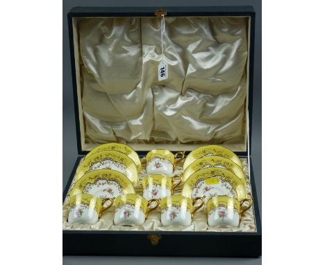 A cased set of six Coalport cups and saucers, yellow ground with gilt highlighting and handles and small floral pattern, 11.5