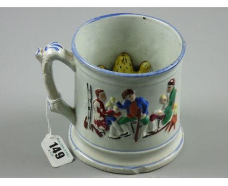 A Staffordshire pottery frog mug with relief pattern of gentlemen in a tavern and yellow frog to the interior, 12 cms high, 1