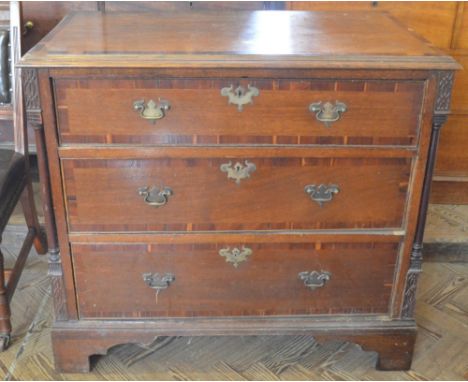 An Oak cross banded and inlaid chest of three long drawers with Tuscan column supports and fret carving on shaped bracket fee