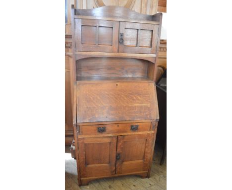 An Arts and Crafts Oak bureau bookcase with fall front enclosing pigeon hole interior, above and below cupboards, single draw