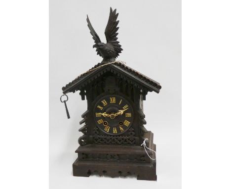 Black forest cuckoo clock surmounted by an eagle above the cuckoo's door and dial with Roman numerals, within a carved dark o