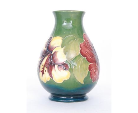 A Moorcroft baluster vase decorated in the Hibiscus pattern with a crimson and a yellow and amethyst flower heads against a g