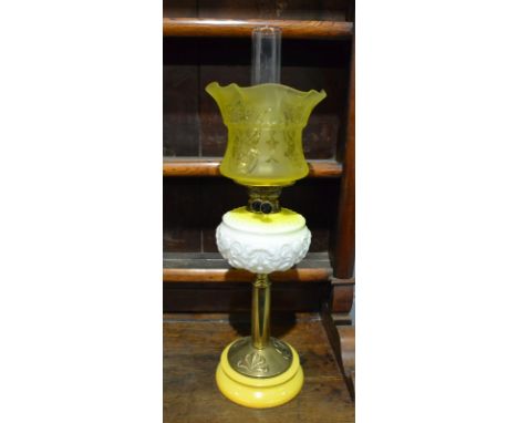 A late 19th Century brass oil lamp with yellow shade and reservoir on circular base, height 70cm