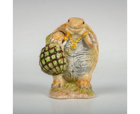 Depicts a green-brown tortoise standing on his back legs holding a rope bag. Beswick backstamp. This item has its original bo