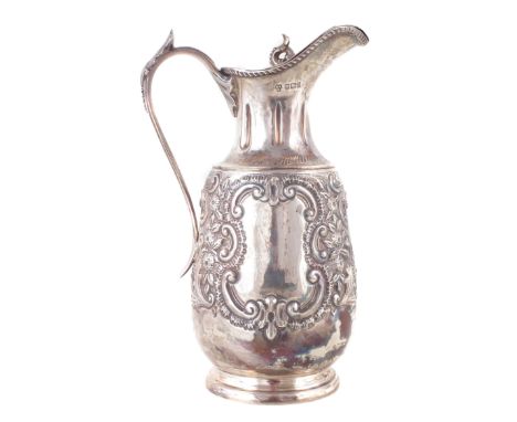 An early 20th Century silver water jug Of baluster form, with central cartouche and repoussé floral detailing to the body, ra