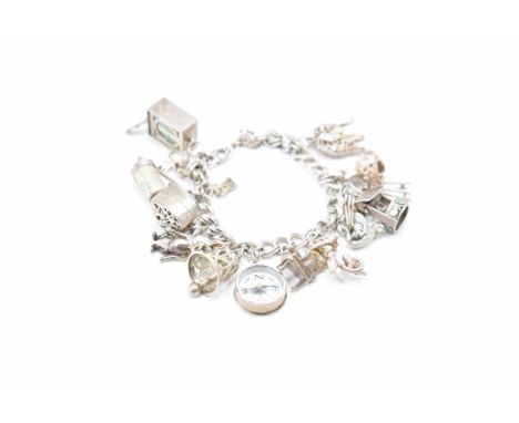 A vintage silver charm bracelet. The bracelet having double curb links with fifteen silver and white metal charms, to include