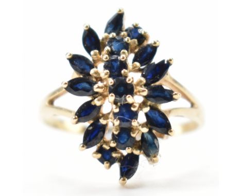 A hallmarked 9ct gold and sapphire cluster ring. The ring in the form of an ornate marquise cluster to split shoulders and pl