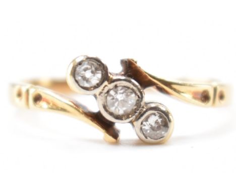 An 18ct gold and diamond three stone ring. The ring set with three single cut diamonds to a crossover setting. Marked 18ct, t