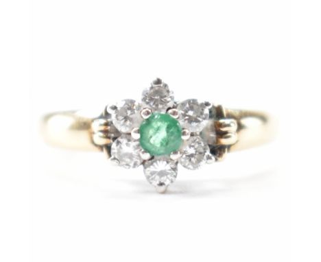 A hallmarked 9ct gold diamond and emerald cluster ring. The ring set with a central mixed cut emerald framed by six round bri