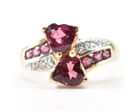 A hallmarked 9ct gold garnet and diamond crossover ring. The ring having two heart cut garnets and illusion set diamonds. Wei