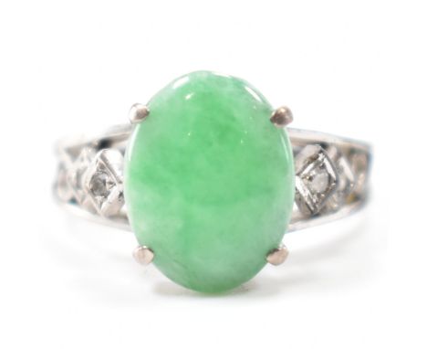 A white gold, jade &amp; diamond ring. The ring having a central prong set jade cabochon flanked by two accent diamonds to ea